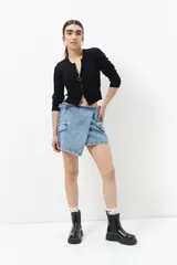 Minifalda de jean celeste con corte asimétrico, bolsillos de parche con solapa y tiras ajustables con hebillas en los laterales.