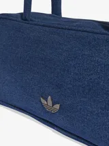 Bolso de hombro tipo cartera confeccionado en denim azul, con diseño rectangular, cierre superior y asas largas. Presenta el logo del Trifolio metálico en la parte frontal.