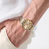 Reloj analógico Guess con caja de 40 mm y malla de acero inoxidable en tono bicolor dorado y plateado. La esfera color champagne presenta un acabado sunray, índices en color verde y bisel estriado.