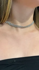 Gargantilla tipo choker de tres hileras de cristales brillantes engarzados en metal plateado.
