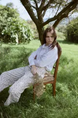 Camisa de algodón con estampado de rayas verticales en color bordó y blanco. Presenta un diseño de manga larga con puños abotonados, cuello camisero y un detalle de volado lateral que recorre el frente desde el cuello hasta el ruedo, acompañando la línea de botones.