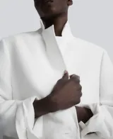 Blazer recta color blanco de lino europeo y viscosa responsable, con solapa, manga larga con hombreras, tres botones en puño, cierre de dos botones y bolsillos de vivo con solapa en delantero.