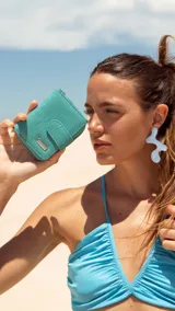 Billetera corta de símil cuero con textura croco, cierre perimetral y solapa con broche a presión. Cuenta con tarjeteros, visor, compartimento para billetes y bolsillo posterior con cierre.