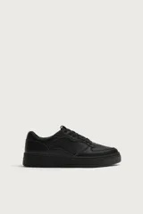 Zapatillas deportivas de estilo retro, color negro, con diseño superior de paneles combinados, cordones al tono y suela gruesa con volumen.