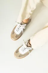Championes urbanos de gamuza color marrón, con detalles en charol negro y bordes dorados. Presentan cordones negros y suela de goma al tono.