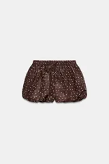 Falda pantalón de tiro medio con diseño abullonado, confeccionada en tela satinada color marrón con estampado de lunares blancos. Cuenta con cintura elástica ajustable mediante cordones.
