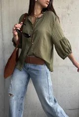Camisa verde de tejido liviano, con cuello romántico con volados, mangas abullonadas tres cuartos con puños fruncidos y cierre frontal con botones.
