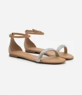 Sandalia plana color nude con tira fina con aplicación de strass y mini espejos, cierre en el tobillo, puntera redonda y taco bajo plano.