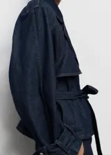 Abrigo corto estilo chaqueta de jean, confeccionado en algodón denim azul oscuro. Presenta cuello con solapas, cierre frontal, trabillas en los hombros y mangas largas con trabillas ajustables.