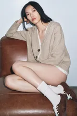 Chaqueta tipo cárdigan de lana en color beige, con diseño de tejido combinado que incluye una capa interior de tela clara. Presenta escote en pico, manga larga y cierre frontal con botones oscuros.