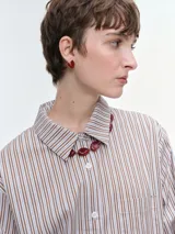 Camisa oversize de popelina de algodón con diseño de rayas verticales, cuello clásico, cierre frontal con botones, manga larga con puños anchos y bolsillo aplicado en el pecho.