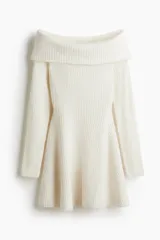 Vestido corto color blanco hueso en punto acanalado suave, con escote off-the-shoulder (hombros descubiertos) y doblez. Tiene mangas largas y una falda con vuelo.