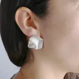 Aros de metal dorado con forma irregular y textura martillada.