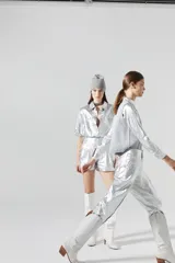 Pantalón slouchy plateado de lino orgánico con efecto metalizado y gastado. Tiene tiro medio, pinzas, cierre frontal, bolsillos laterales y traseros, y ajuste en los tobillos.