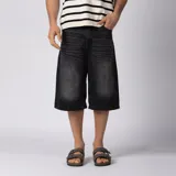 Bermuda de jean baggy color negro con lavado gastado, de corte ancho y largo hasta debajo de la rodilla, con diseño de cinco bolsillos y detalles de recortes en los bolsillos traseros.