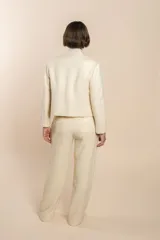 Chaqueta de sastrería color crema, entallada y con cuello erguido. Prenda forrada de lana fina sin teñir.