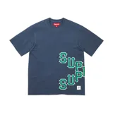 Camiseta de manga corta Supreme, color azul marino, con estampado gráfico lateral en color verde y blanco. Presenta un corte holgado y una etiqueta pequeña en el borde inferior.