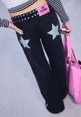 Jean de corte recto y tiro bajo, color negro, con detalle de tachas metálicas en la cintura y una banda lateral de brillos a lo largo de la pierna.