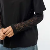 Camiseta negra de algodón con diseño 2 en 1, que combina un cuerpo de remera de manga corta con mangas largas integradas de encaje floral.