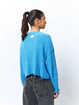 Sweater color crema de tejido de punto acanalado, corte cropped, cuello redondo y mangas largas.