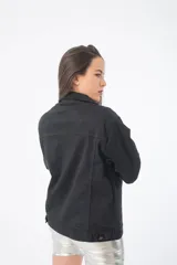 Campera de jean negra con detalles de cuero sintético plateado en la parte superior y tachas plateadas en los hombros.