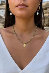 Collar corto de cristalitos facetados en tonos verdosos y dorados, con dije colgante en forma de sol y cierre de acero.