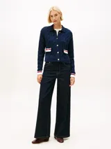 Cárdigan de punto trenzado en color azul marino, con cuello tipo polo y cierre frontal de botones dorados. Presenta dos bolsillos frontales con solapas decoradas en blanco, rojo y azul, y puños con el mismo detalle tricolor.