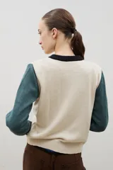 Saco de punto con diseño color block, presenta cuerpo en color bordó, mangas en color rojo y tapeta frontal con cuello redondo en color rosado. Posee cierre frontal con botones y puños acanalados.