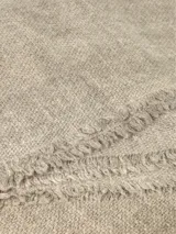 Bufanda fina de tejido ligero y suave, color beige, con bordes deshilachados.