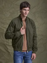 Campera tipo bomber color verde militar, con cierre frontal completo, cuello alto y puños y ruedo acanalados. Presenta un acabado encerado que le otorga un aspecto distintivo.