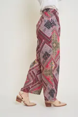 Pantalón italiano de seda con estampado geométrico en tonos verde, rosa, amarillo y negro. Tiene cintura elastizada y bolsillos laterales.