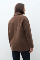 Chaqueta color chocolate de simil gamuza, con cuello camisero, botones frontales y bolsillos laterales.
