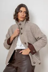 Campera de paño de lana color marrón con diseño oversize. Presenta cuello alto, cierre frontal con botones y detalles en pana azul marino en los puños y en las tapas de los bolsillos frontales.