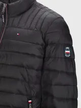 Campera acolchada negra de Tommy Hilfiger, con cuello alto, cierre frontal con cremallera y dos bolsillos laterales con cremallera. Logo de Tommy Hilfiger bordado en el pecho.