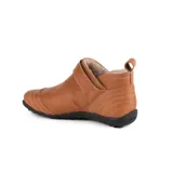 Botita baja Marcel confeccionada en cuero vacuno color marrón, con interior de corderito ultrasuave. Presenta costuras pespunteadas decorativas, tira lateral con hebilla metálica dorada y detalles de elástico negro. Suela plana de goma negra.