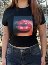 Remera negra corta con estampado frontal de labios rojos y la frase "Don't be jealous.", manga corta y cuello redondo.