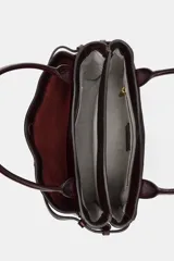 Bolso de mano pequeño (mini city) de piel color borgoña oscuro, con doble asa superior y detalles de tiras ajustables en los laterales. Presenta un acabado brillante y herrajes dorados.