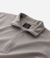 Buzo de cuello alto con cierre frontal parcial, manga larga y puños ajustados. Presenta un diseño minimalista en color verde militar.