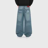 Jean baggy de denim 100% algodón, de color azul con efecto deslavado y diseño amplio. Cuenta con bolsillos traseros con detalles bordados de estrellas y texto, además de efecto desgastado en las piernas.