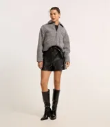 Short corto color marrón oscuro, confeccionado en poliuretano (PU) con textura que imita el cuero. Presenta cintura elástica en la parte trasera, lazo delantero para ajustar y recortes decorativos.