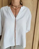 Collar estilo corbatín confeccionado en tiento de cuero color suela, con detalle de cuentas metálicas plateadas distribuidas a lo largo de las tiras.