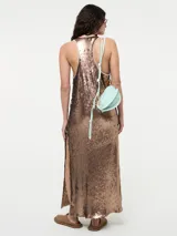 Vestido largo de corte recto con escote redondo y tirantes anchos, completamente cubierto de lentejuelas brillantes. Presenta tajos laterales en el ruedo.