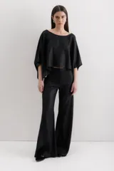 Pantalón de pierna ancha con acabado brillante, confeccionado en lino. Presenta un diseño de tiro medio con cierre de botón y cremallera, bolsillos traseros y etiqueta de marca en la cintura.