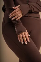 Conjunto deportivo marrón compuesto por calza larga, musculosa y campera con cierre.