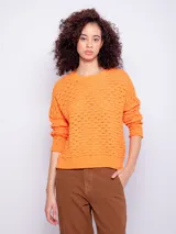 Sweater de tejido de punto color naranja, con diseño de calados, manga larga y cuello redondo.