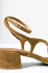 Sandalias de taco cuadrado medio, confeccionadas en gamuza color azul. Presentan tiras finas que cruzan el empeine, una pulsera ajustable al tobillo y detalle de cuentas decorativas en la tira frontal.