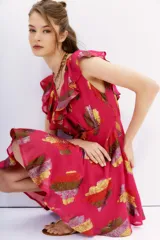 Vestido corto de viscosa con jacquard en lurex multicolor, de escote en frente y espalda, con volados en los hombros. El estampado presenta motivos abstractos en tonos fucsia, dorado, rojo y verde.