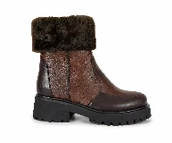Bota corta de cuero vacuno en tonos marrones, con cuello de corderito sintético, suela de goma tipo track y punta redonda.