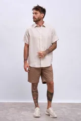 Camisa de lino color beige, de manga corta, cuello clásico y botones frontales.