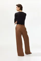 Pantalón sastrero de corte holgado color marrón, con pretina prolongada, cierre frontal y pinzas en las perneras amplias.